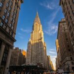 Dramatic upward photograph of the iconic Art Deco spire of the Chrysler Building glowing in afternoon sunlight in Manhattan