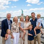 Happy multi-generational family smiling at Battery Park with Statue of Liberty in harbor background