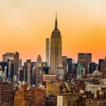 Stylish solo traveler standing confidently amidst the historic architecture and vibrant morning street life of Manhattan